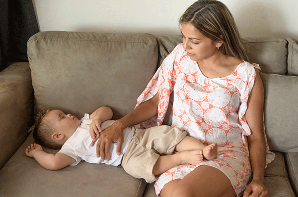 woman on couch with child playing