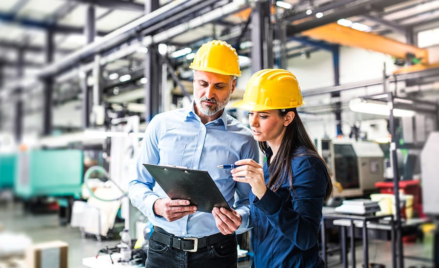 male and female on site in hard hats looking at a checklist