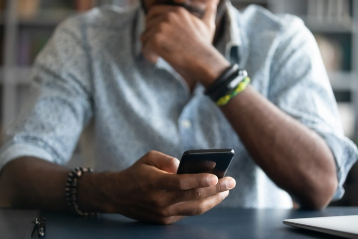 Following up after an interview - African guy holding a device and in his hand and looking at it image