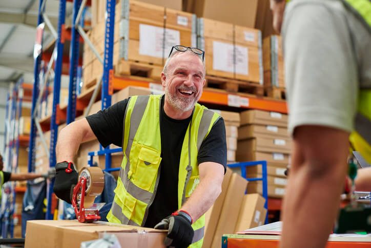 man in warehouse looking happy in a high vis vest
