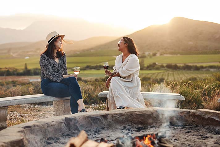 2 women drinking wine at campsite