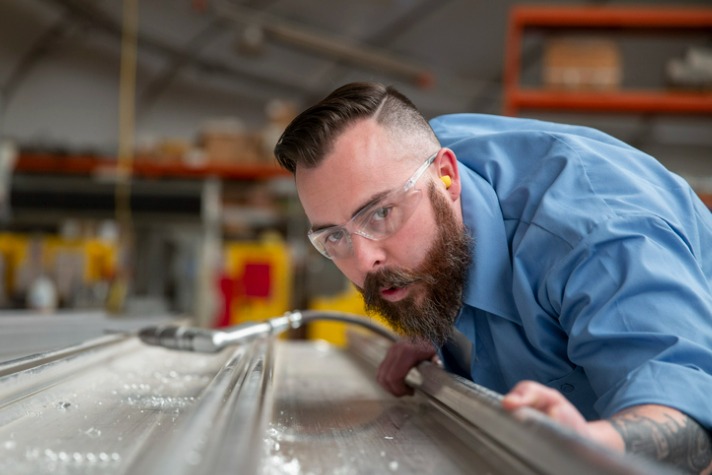 bearded man eyeing the angle of a product in a manufacturing plant - best jobs for people with OCD image