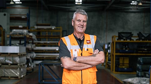 Employer standing in warehouse with arms folded