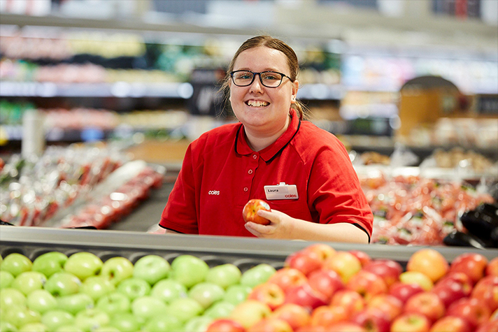 a person holding an apple in a grocery store